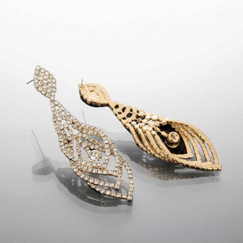 Gold earrings with intricate designs on a reflective surface