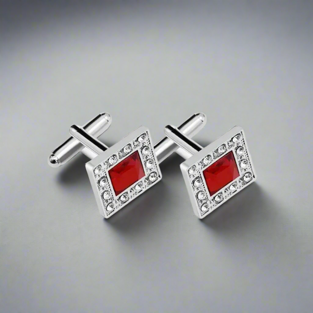 Silver cufflinks with red square stones on a gray background