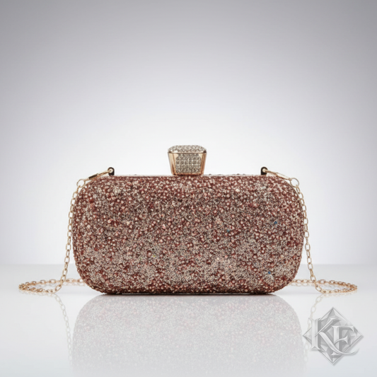 A sparkling clutch bag covered in rose gold and champagne rhinestones, featuring a gold-tone chain strap and a decorative clasp on a light gray background.