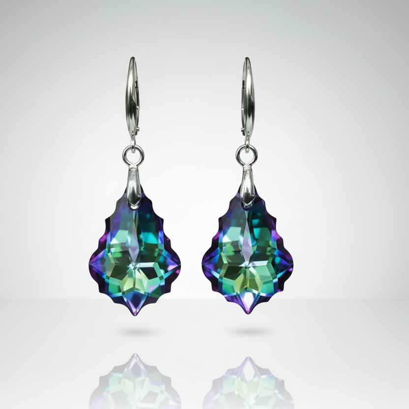 Pair of colorful crystal earrings on a reflective surface with a light gray background