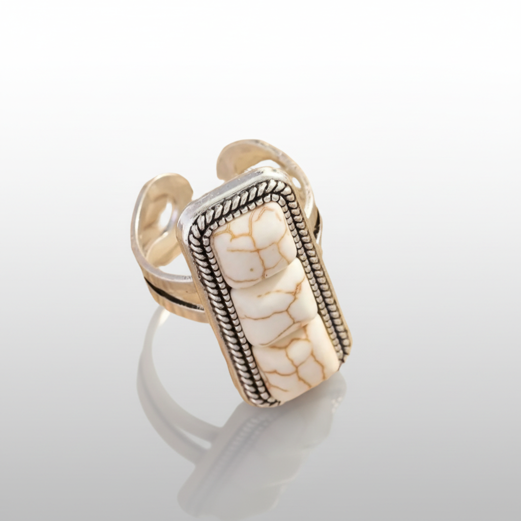 Gold and silver ring with a textured stone design on a white background