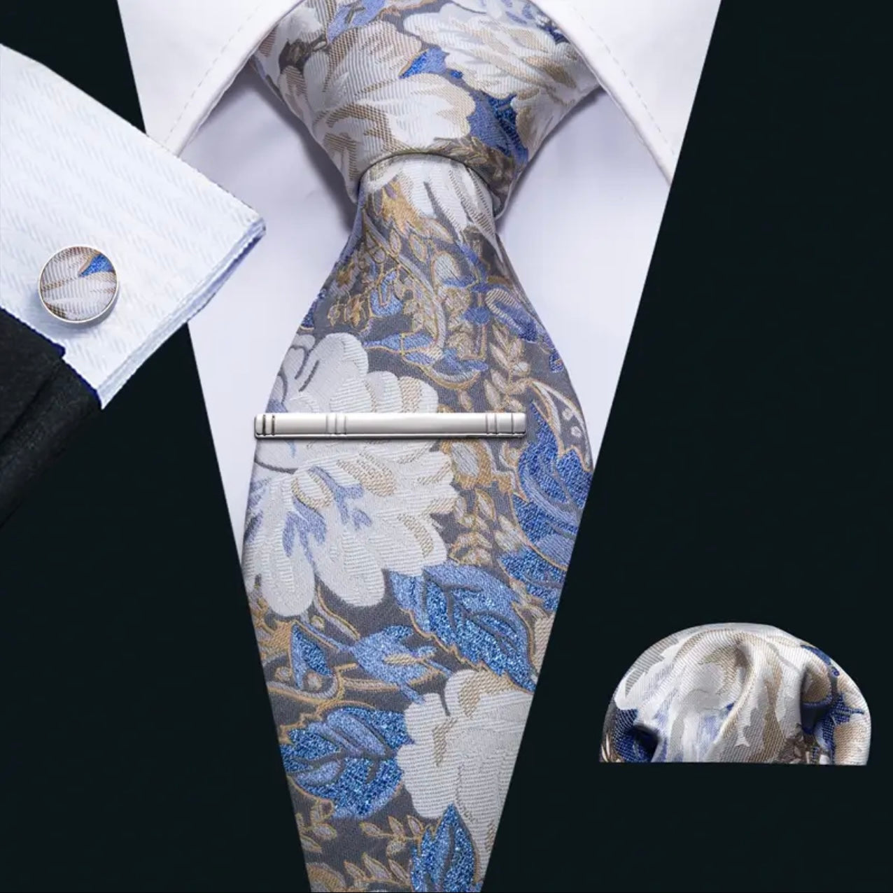 Floral patterned tie with matching pocket square and cufflinks on a white shirt.